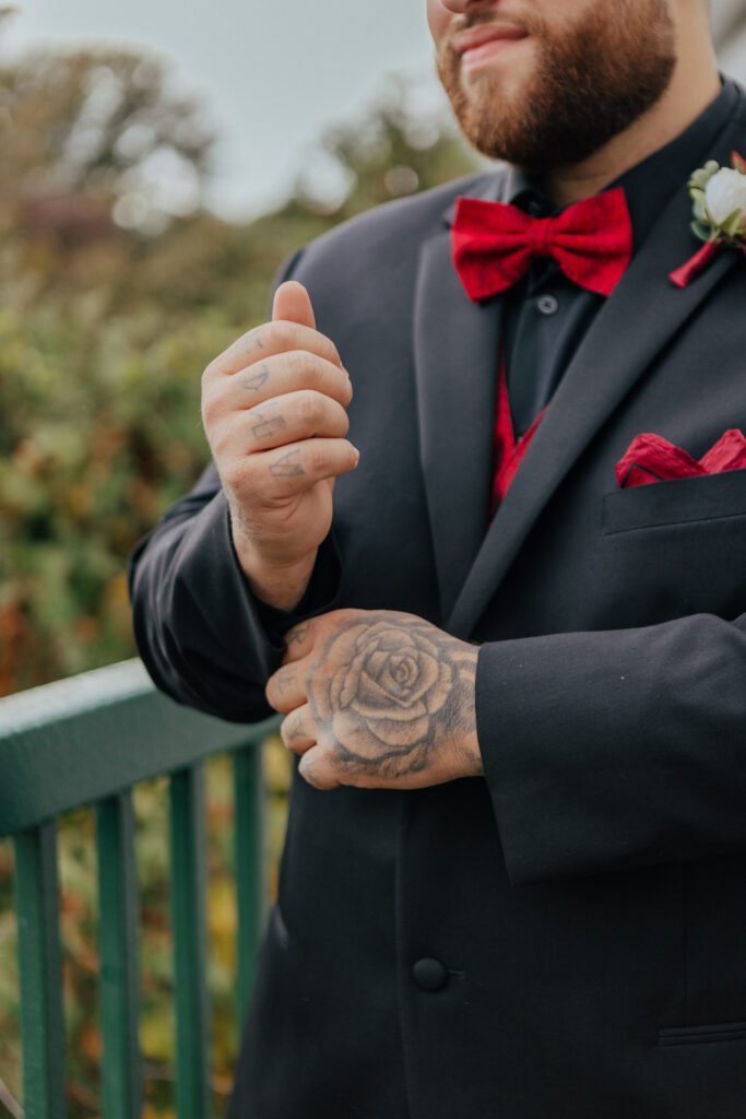 Groom adjusting suit sleeves as he is getting ready outside at Black Swan Country Club in Georgetown, Massachusetts.
