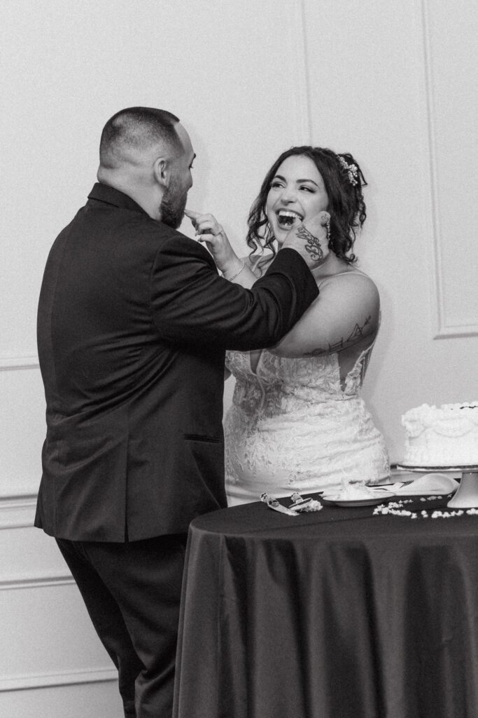 Bride and groom laugh as they feed each other cake at Black Swan Country Club in Georgetown, Massachusetts.
