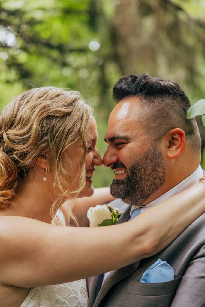 Bride and groom laughing and touching noses in the woods at Bird Park in Walpole, Massachusetts.