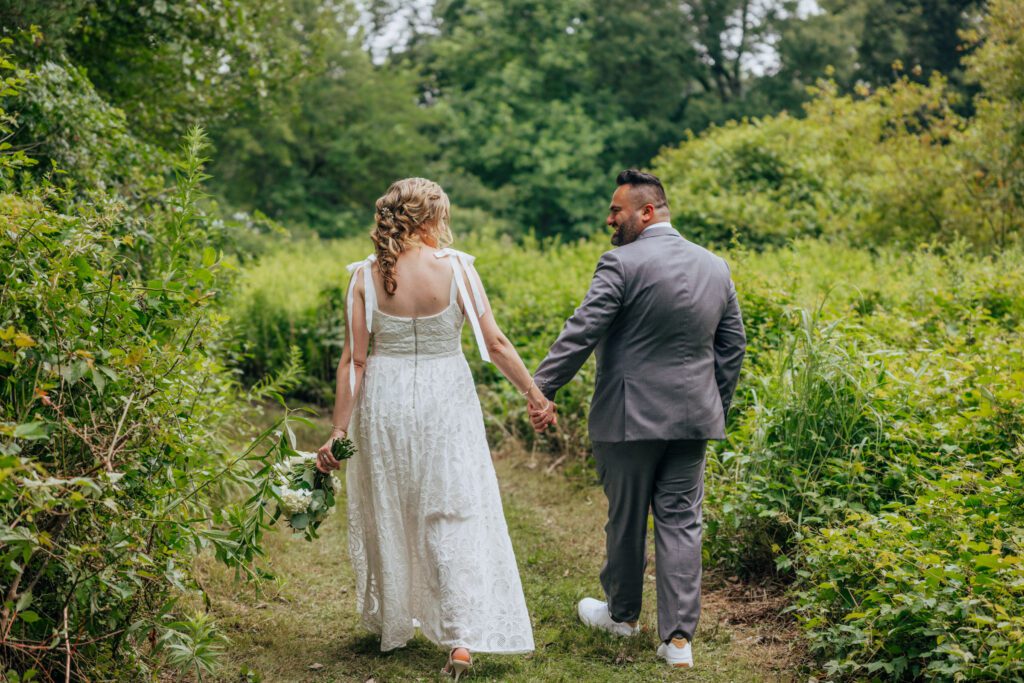 Bride and groom walking into a whimsical flower field looking at each other at Bird Park in Walpole, Massachusetts.