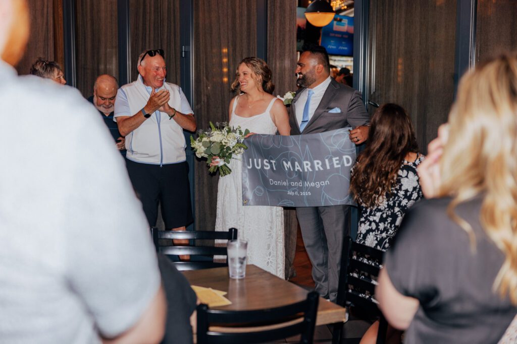 Bride and groom entering Citizen Crust in Foxboro, Massachusetts. holding a "Just married" sign.