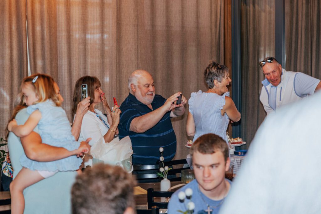 Guest taking photos of bride and groom entering as they hold a "just married sign".