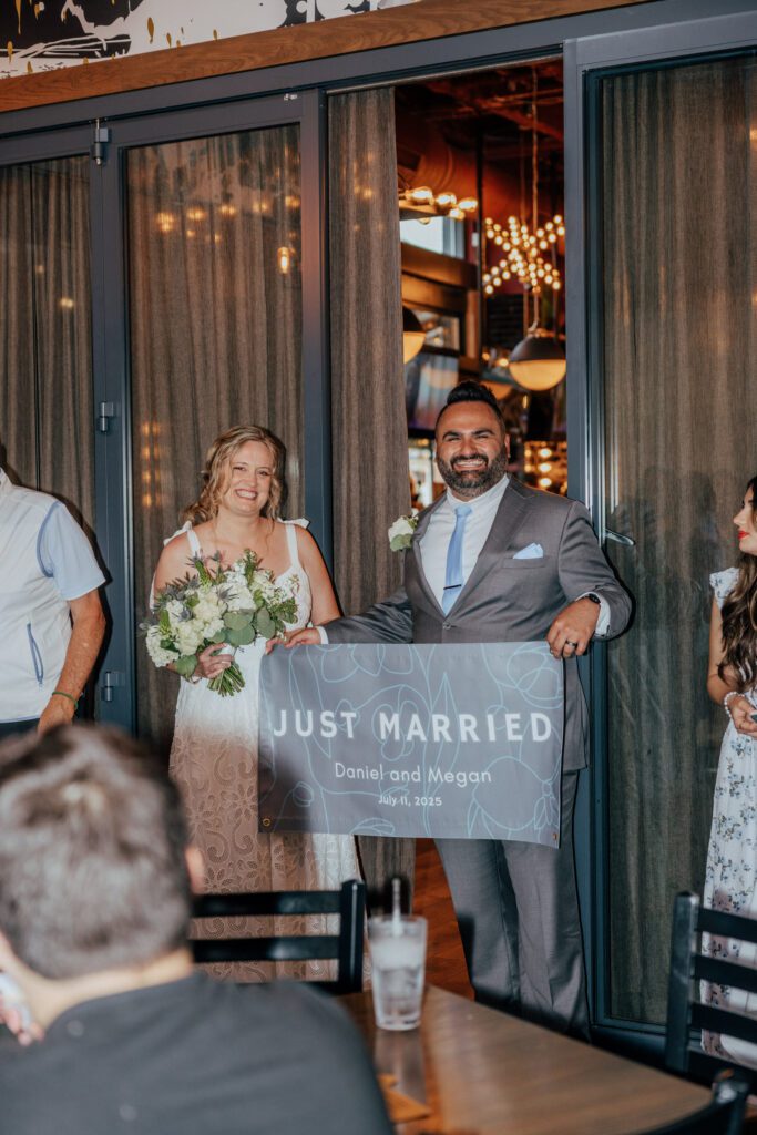 Groom and bride entering Citizen Crust in Foxboro, Massachusetts. holding a "Just married" sign.