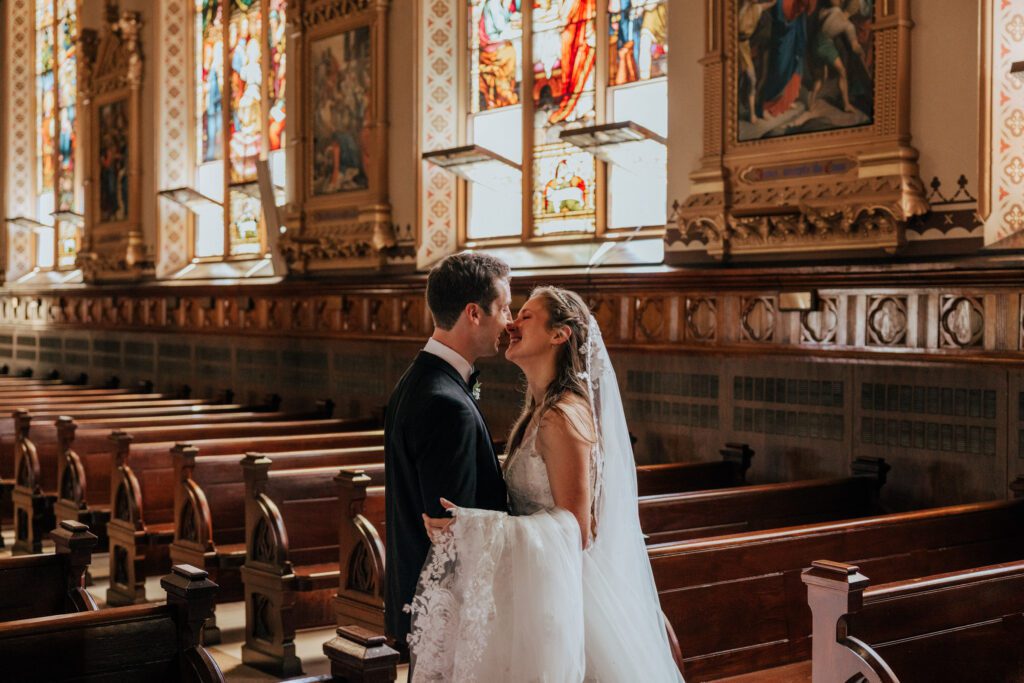 Bride and groom kissing in church at Quinet Saint John Garden of Our Lady in Massachusetts.