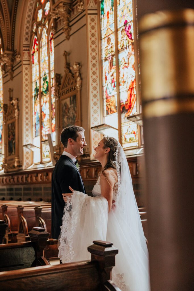 Bride and groom looking at each other and smiling romantically at Quinet Saint John Garden of Our Lady in Massachusetts.