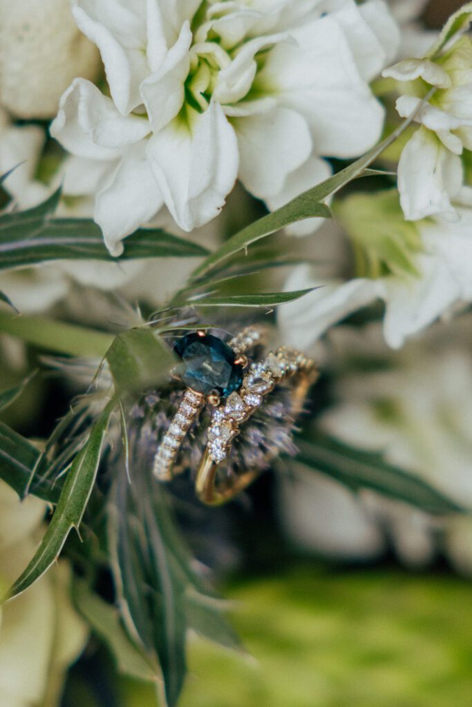 Close up of blue wedding ring on purple flower in bridal bouquet at Bird Park in Walpole, Massachusetts.