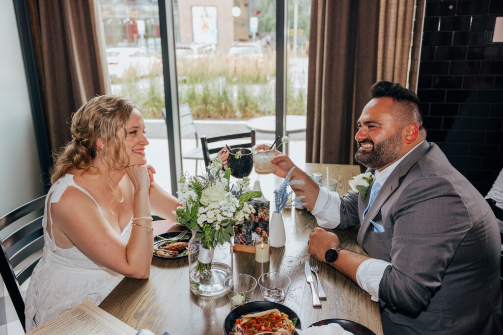Bride and groom cheering their drinks and smiling at each other after Bird park elopement.