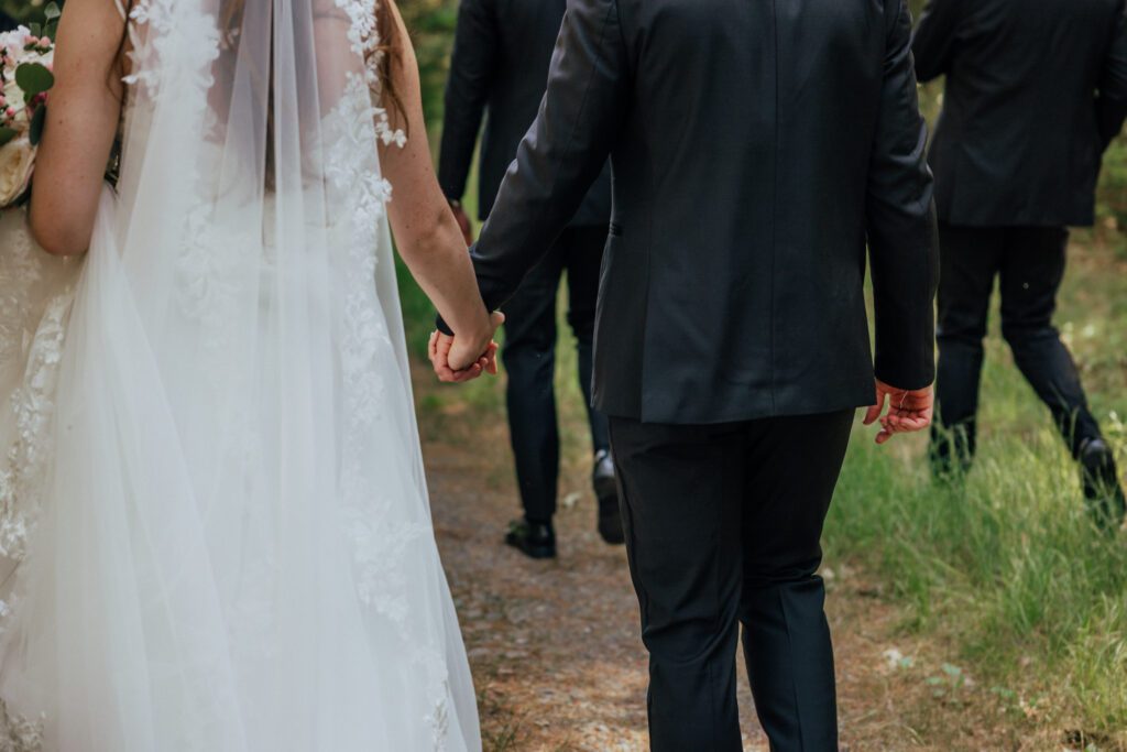 Bride and groom holding hands as they walk in the woods in Massachusetts.