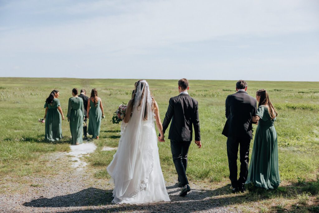 Bride and groom holding hands and walking towards a pond in Massachusetts.