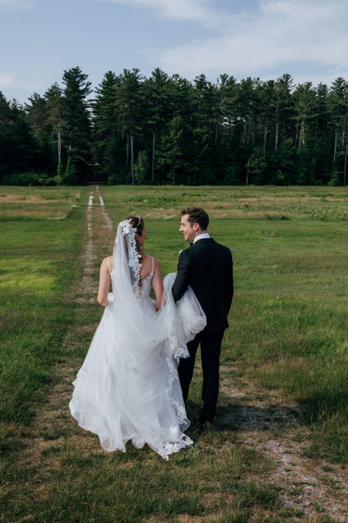 Bride and groom looking at each other as they walk in a field in Massachusetts.