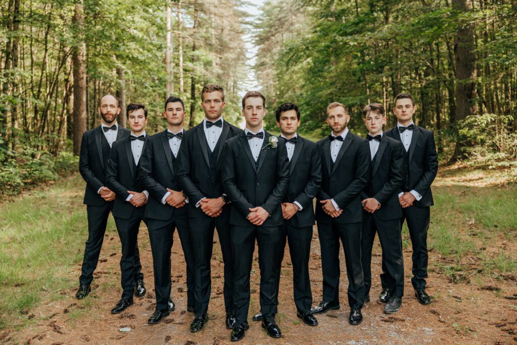 Groom and groomsmen standing in a lineup in the middle of the woods in Massachusetts.