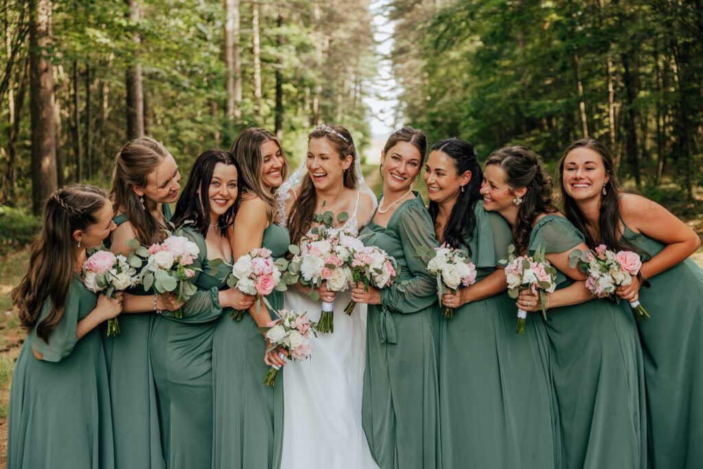 Bride and bridesmaid laughing with each other in the woods in Massachusetts.