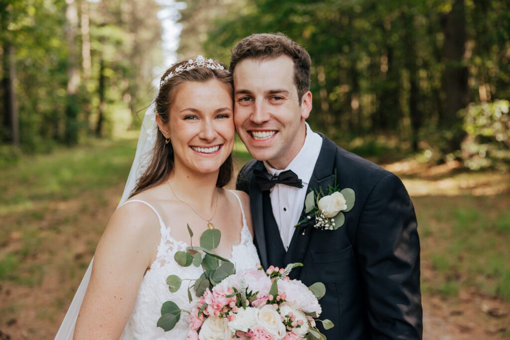 Bride and groom smiling with their heads together in the woods in Massachusetts.