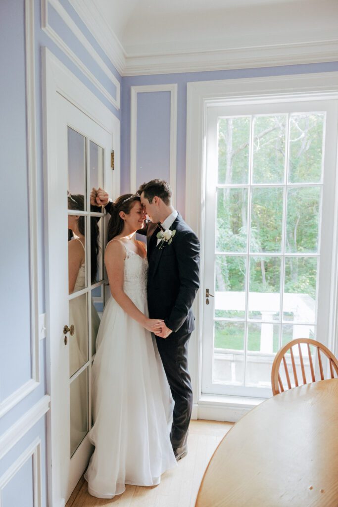 Romantic bride and groom kissing against a window in Massachusetts.