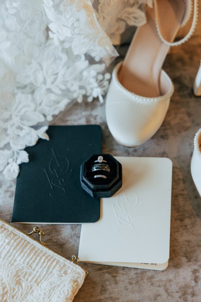 Close up of wedding rings, vows, wedding shoes, and veil at Black Swan Country Club in Georgetown, Massachusetts.