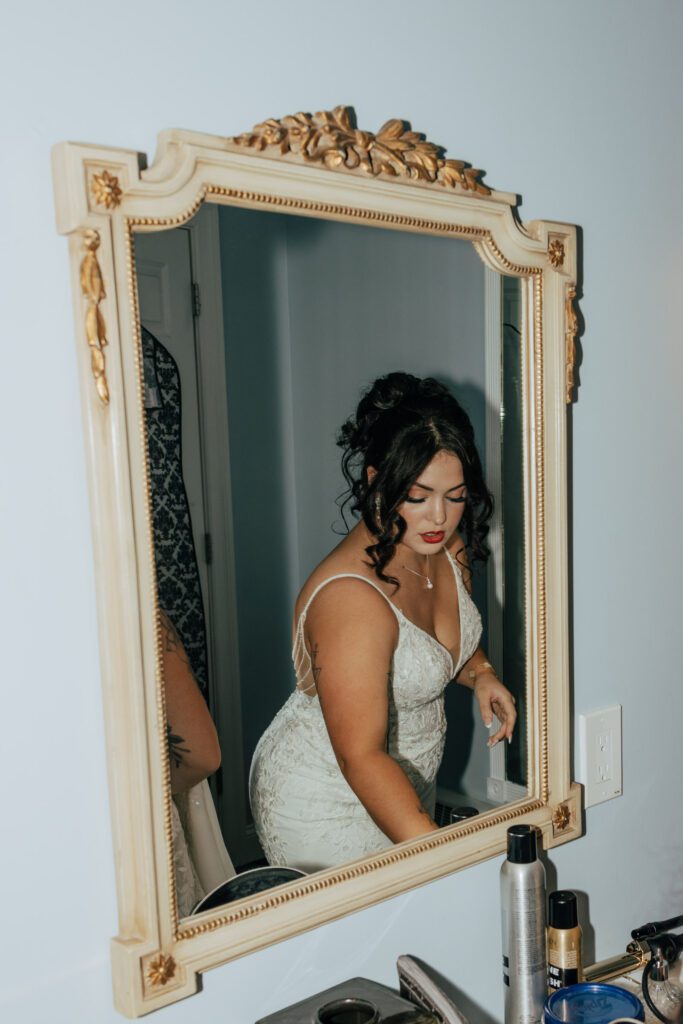 Bride's reflection in a mirror getting ready in bridal suite at Black Swan Country Club in Georgetown, Massachusetts.