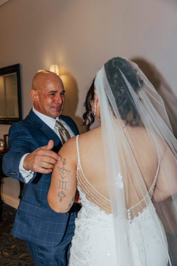 A bride and her father sharing a first look as her father smiles at Black Swan Country Club in Georgetown, Massachusetts.