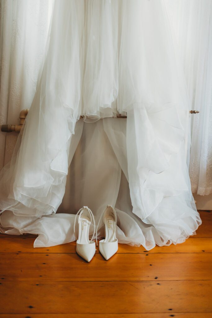 A bride's shoes and wedding gown in the getting ready suite at The Evermore at Peirce Farm Estate in Topsfield, Massachusetts.