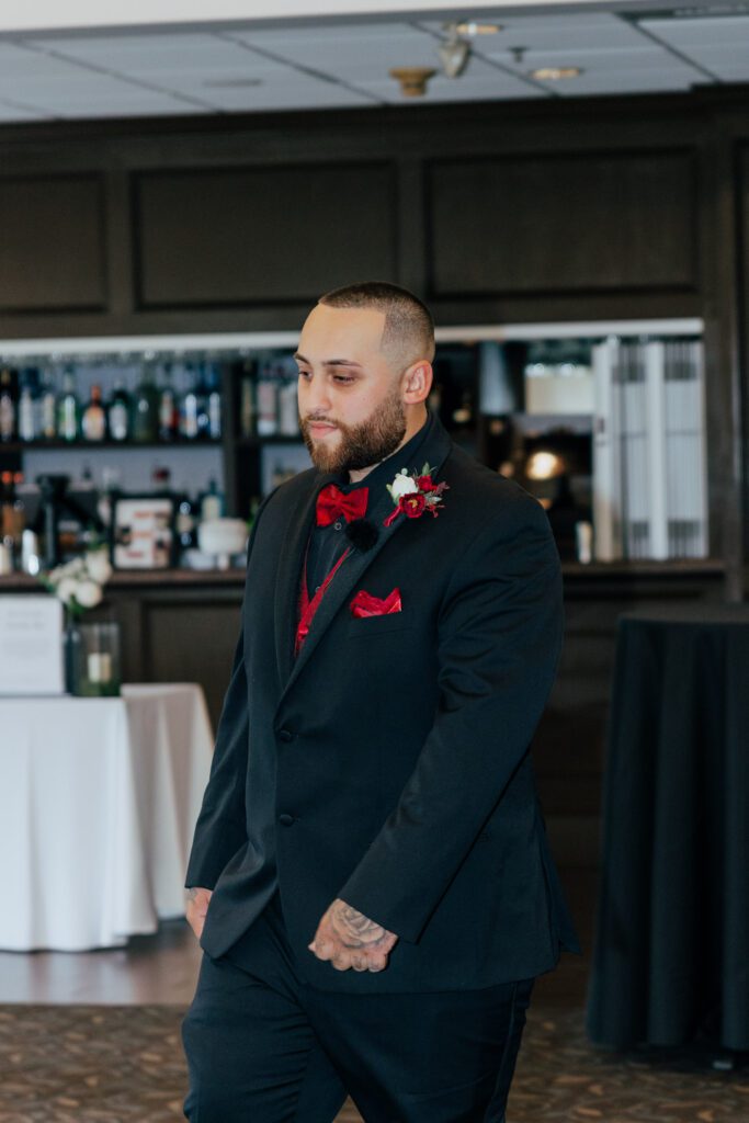 Groom walking down the aisle during romantic indoor ceremony at Black Swan Country Club in Georgetown, Massachusetts.