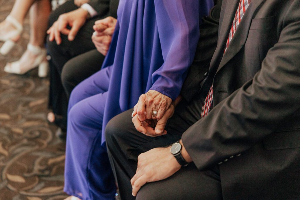 Grandma holding hand during romantic indoor ceremony at Black Swan Country Club in Georgetown, Massachusetts.
