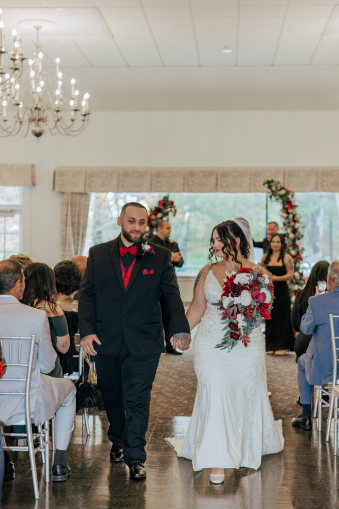 Bride and groom walking down the aisle after getting married in romantic indoor ceremony at Black Swan Country Club in Georgetown, Massachusetts.