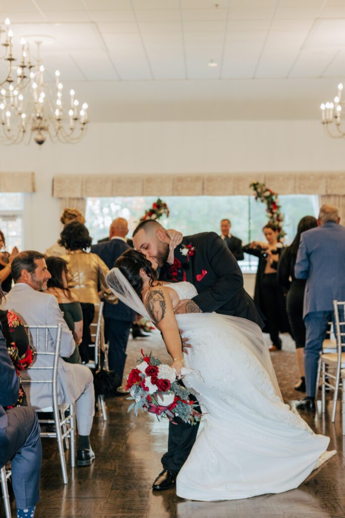 Groom dips bride and kisses her in the aisle after romantic wedding ceremony at Black Swan Country Club in Georgetown, Massachusetts.