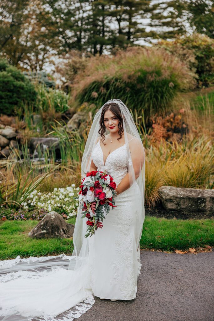 A bride outside standing in front of greenery at Black Swan Country Club in Georgetown, Massachusetts.