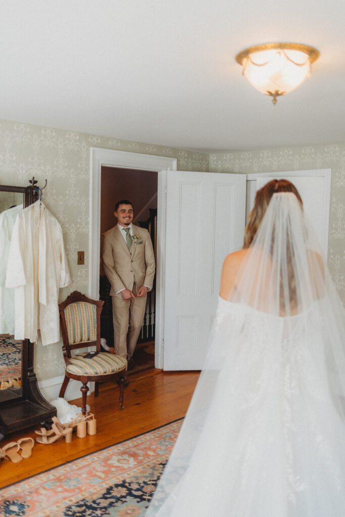 Bride's brother smiling and walking through the door for a first look with the bride at The Evermore at Peirce Farm Estate in Topsfield, Massachusetts.