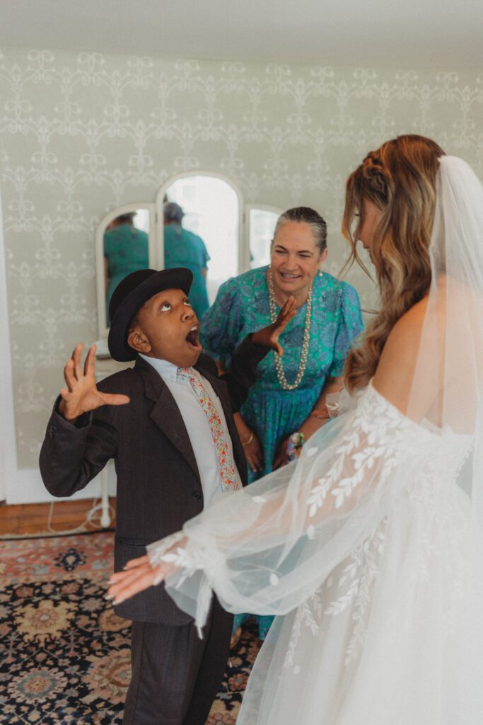 A brides younger brother happy reaction to seeing the bride in her dress during first look at The Evermore at Peirce Farm Estate in Topsfield, Massachusetts.