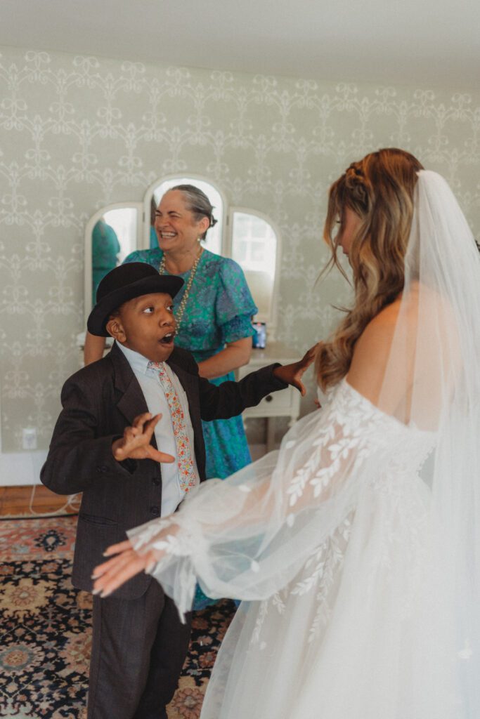 A brides younger brother surprised reaction to seeing the bride in her dress during first look at The Evermore at Peirce Farm Estate in Topsfield, Massachusetts.