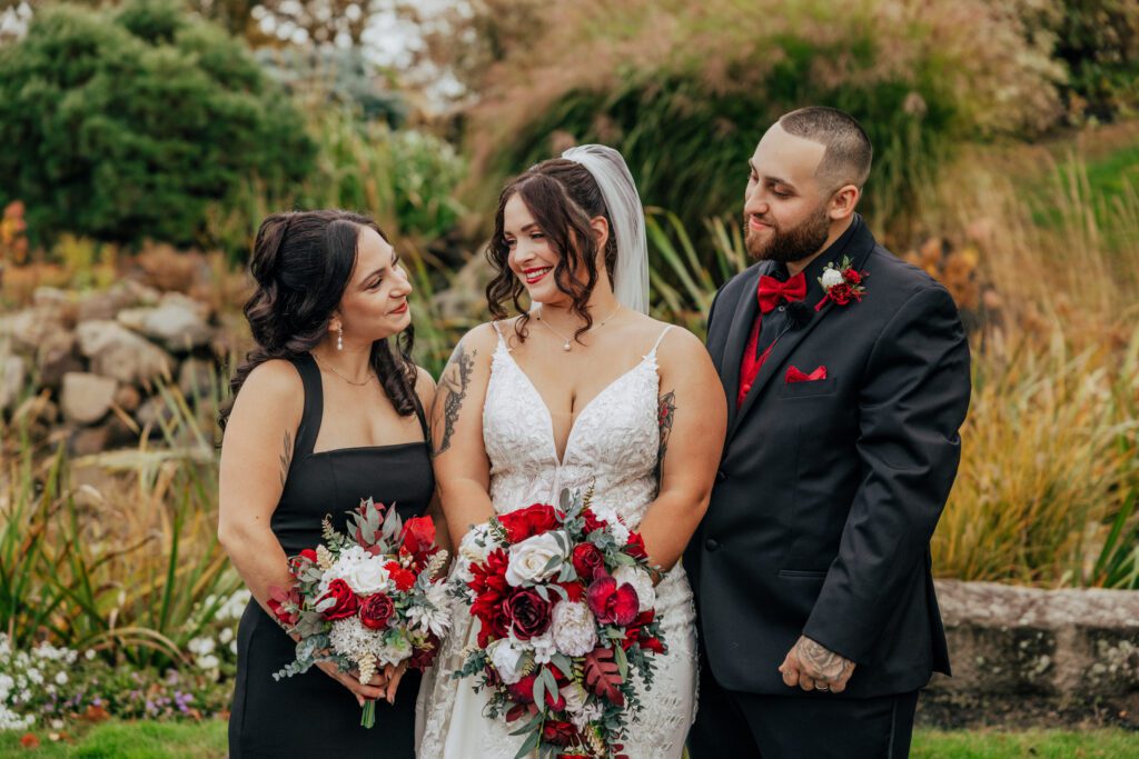 Bride, groom, and family smiling at each other standing outside in front of greenery at Black Swan Country Club in Georgetown, Massachusetts.