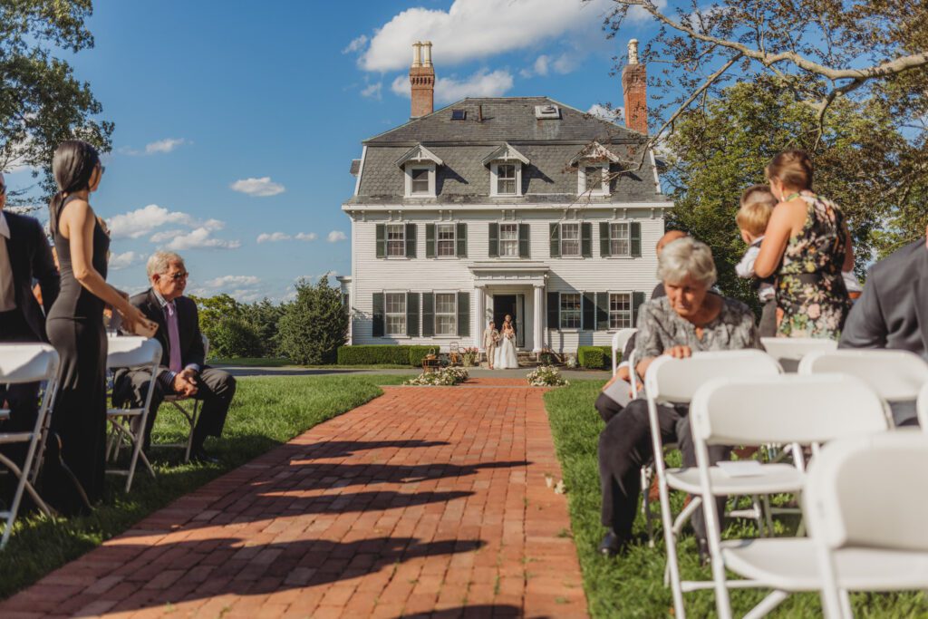 Bride walking out of Peirce Farm Estate in Topsfield, Massachusetts during summer wedding ceremony.