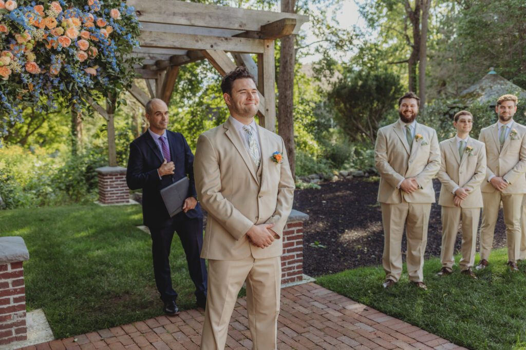 Groom smiling as bride walks down the aisle during a romantic outdoor ceremony at Peirce Farm Estate in Topsfield, Massachusetts.