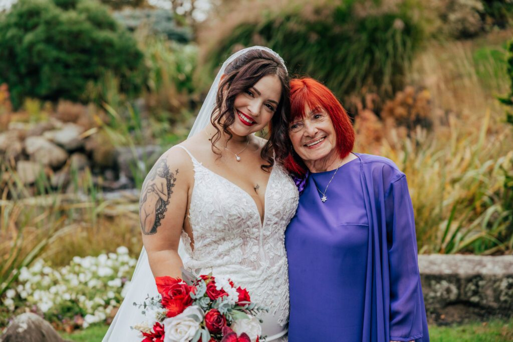 Bride and her grandmother smiling outside in front of greenery at Black Swan Country Club in Georgetown, Massachusetts.