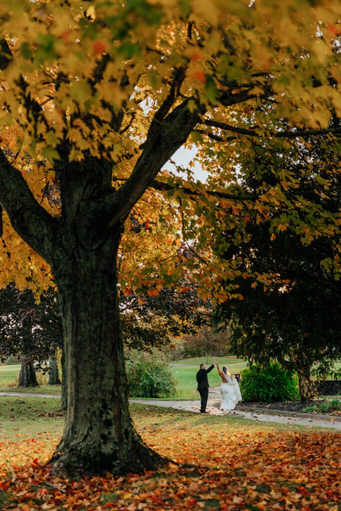 Bride and groom spinning outside at fall wedding during golden hour at Black Swan Country Club in Georgetown, Massachusetts.