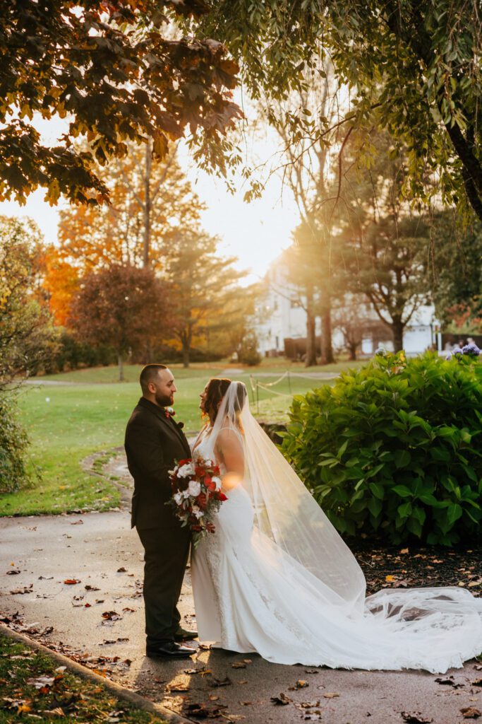 A bride and groom smiling at each other during golden hour at Black Swan Country Club in Georgetown, Massachusetts.