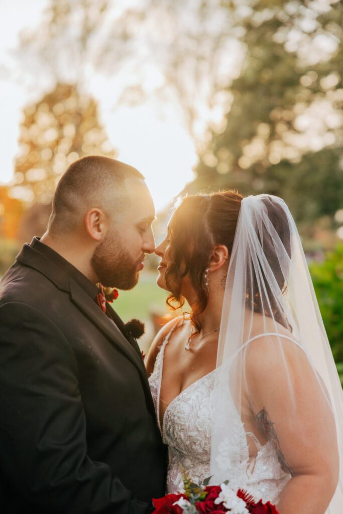 Bride and groom touching noses outside at fall wedding at Black Swan Country Club in Georgetown, Massachusetts.