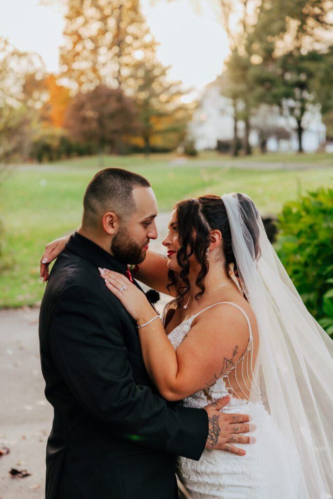 Bride and groom smiling at each other outside during sunset at Black Swan Country Club in Georgetown, Massachusetts.