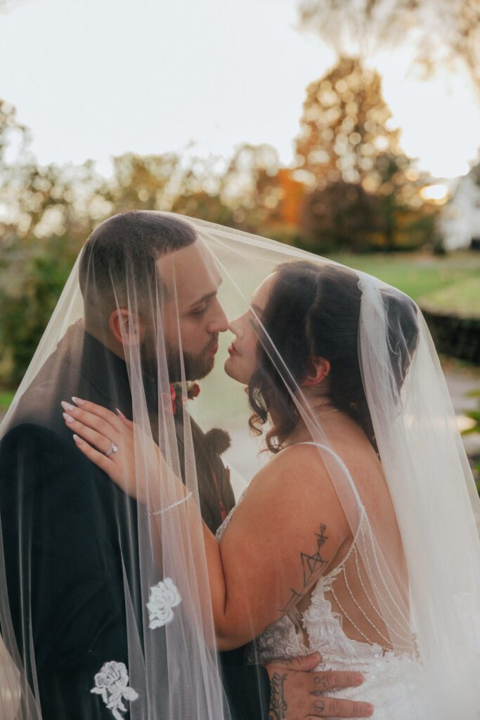 Bride and groom romantically looking at each other under a wedding veil during fall wedding at Black Swan Country Club in Georgetown, Massachusetts.