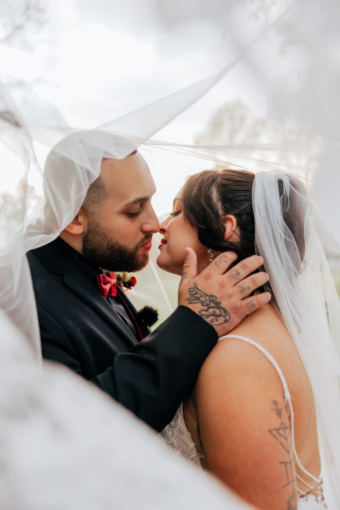 Bride and groom kissing under veil at Black Swan Country Club in Georgetown, Massachusetts.