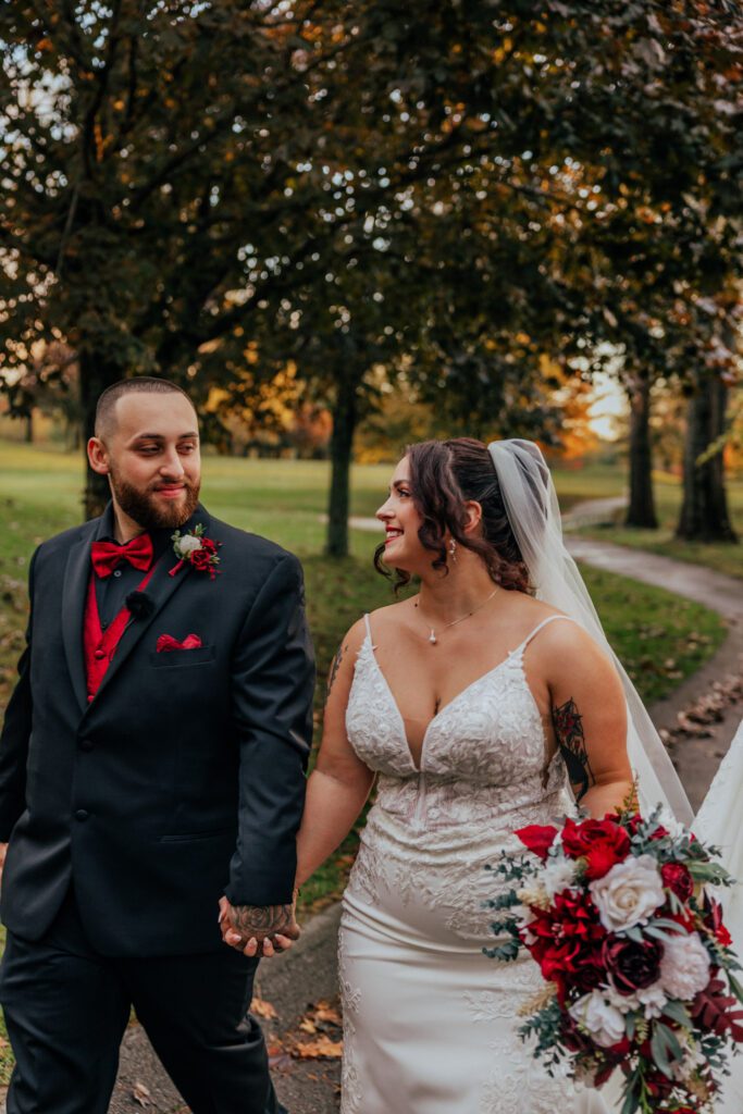 Bride and groom walking and smiling at each other during fall wedding at Black Swan Country Club in Georgetown, Massachusetts.