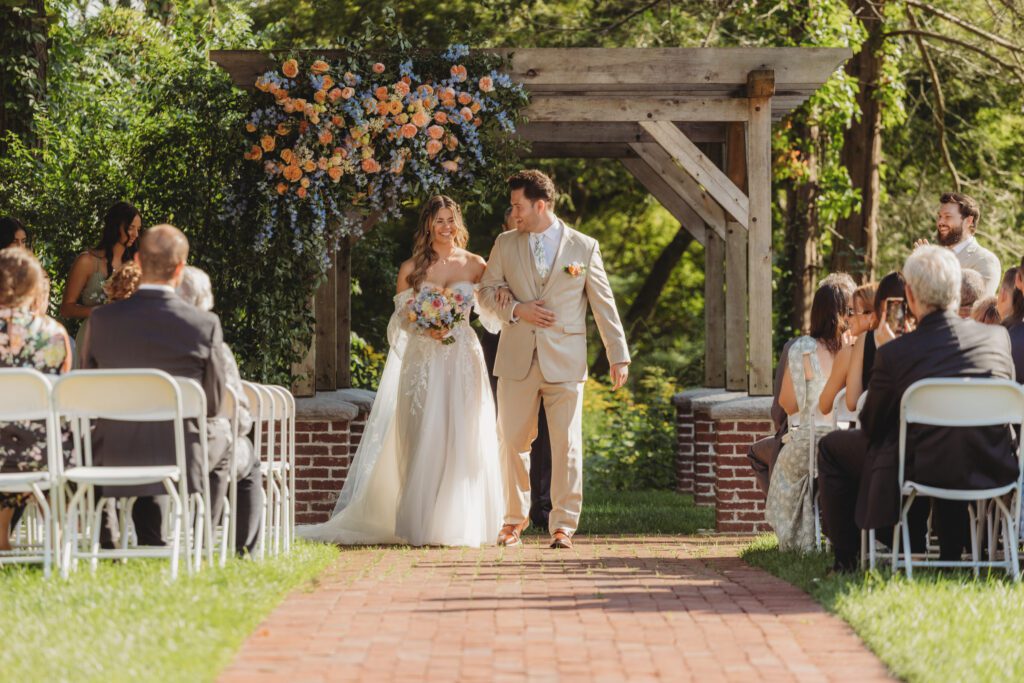 Bride and groom walk down the aisle together as they smile at Peirce Farm Estate in Topsfield, Massachusetts.