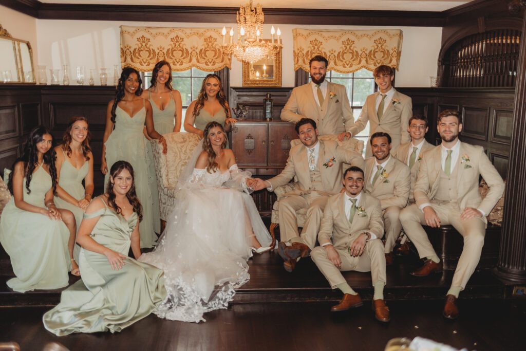 Bride, groom and bridal party sit and pose very elegantly in a charming room at Peirce Farm Estate in Topsfield, Massachusetts.