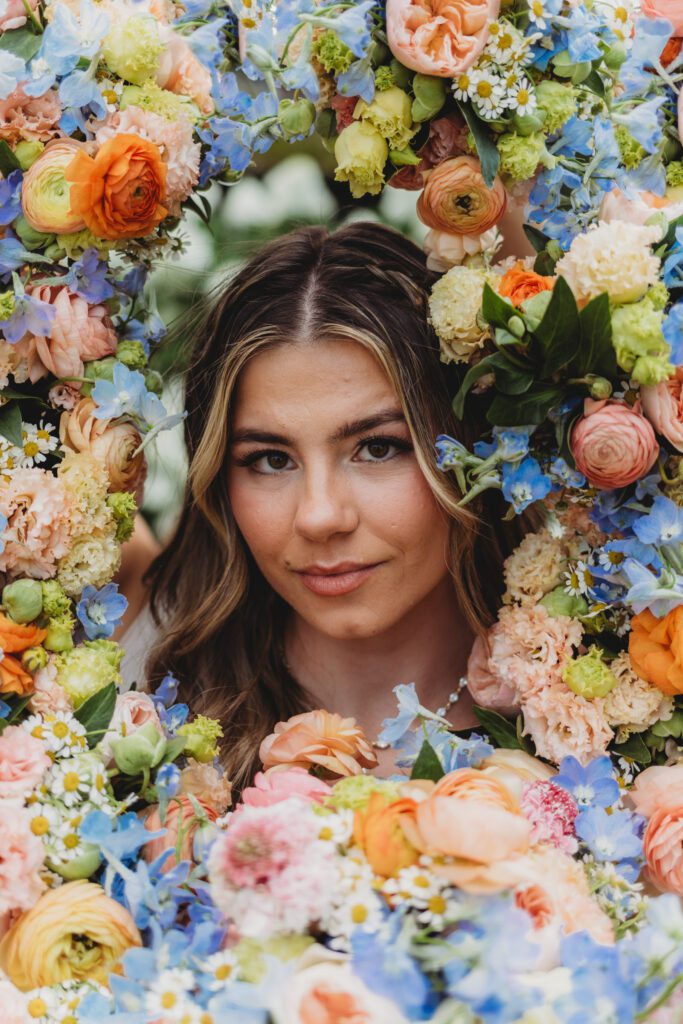 Brides face is framed by bridal party flowers as she looks at the camera at Peirce Farm Estate in Topsfield, Massachusetts.