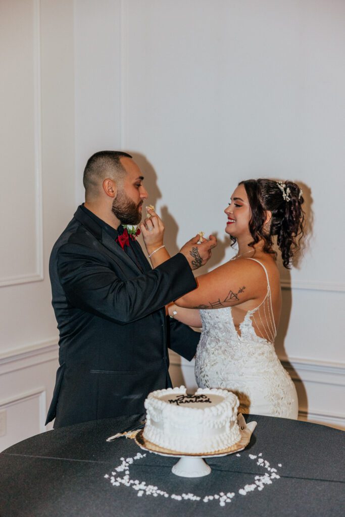 Bride and groom smile as they feed each other cake at Black Swan Country Club in Georgetown, Massachusetts.