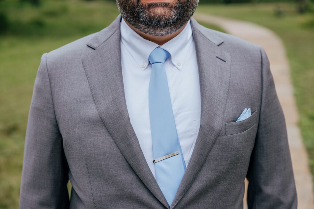 Closeup of grooms gray suit and blue tie at Bird Park in Walpole, Massachusetts.
