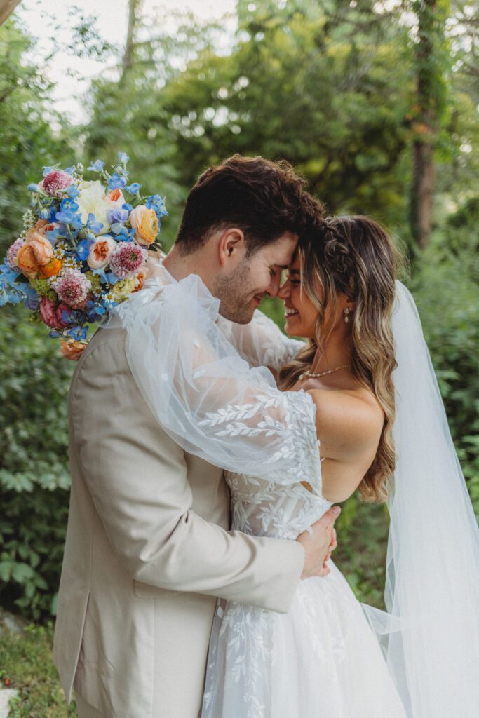 A bride and groom smiling as they hug outdoors at Peirce Farm Estate in Topsfield, Massachusetts.