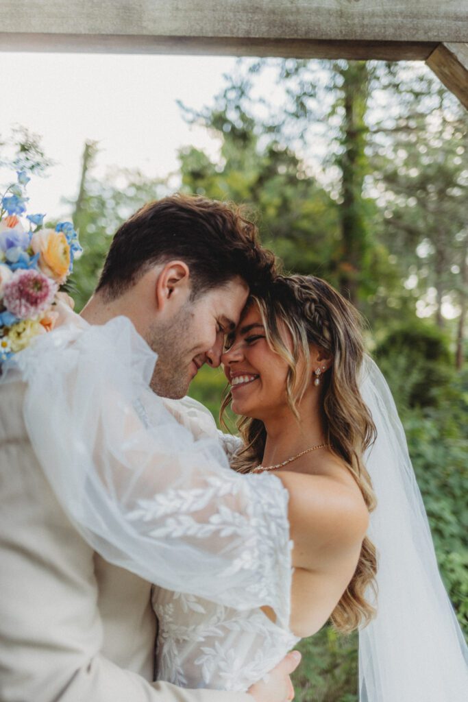 Bride and groom laugh as they hug outside at their whimsical fairytale wedding at Peirce Farm Estate in Topsfield, Massachusetts.