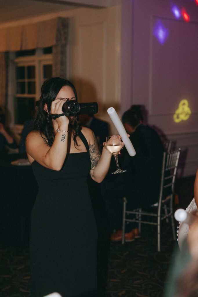Guest on the dance floor with camcorder recording the bride dancing during the reception at Black Swan Country Club in Georgetown, Massachusetts.