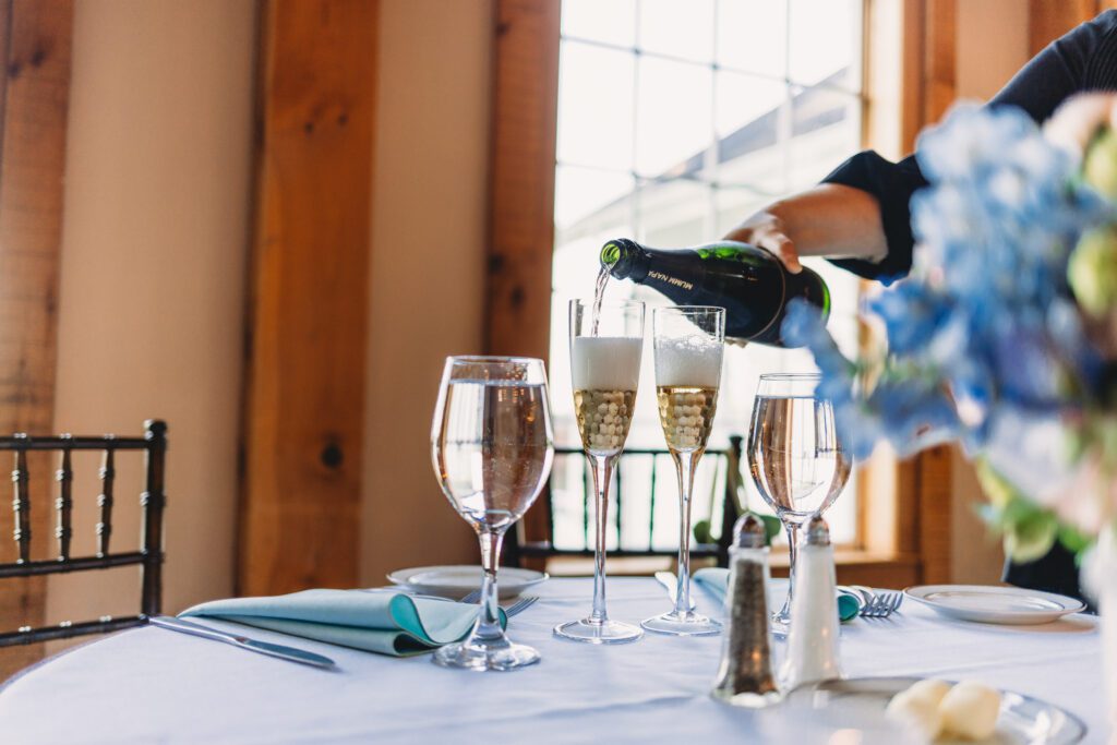 Champagne being poured in whimsical barn wedding at Peirce Farm Estate in Topsfield, Massachusetts.